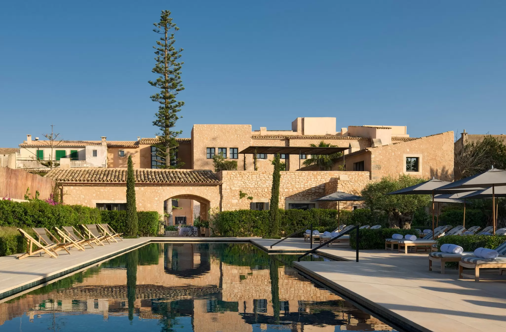 A pool surrounded by sun loungers at a stylish low-rise hotel of sand-colored stone: Can Ferrereta, Santanyí, Mallorca, Spain