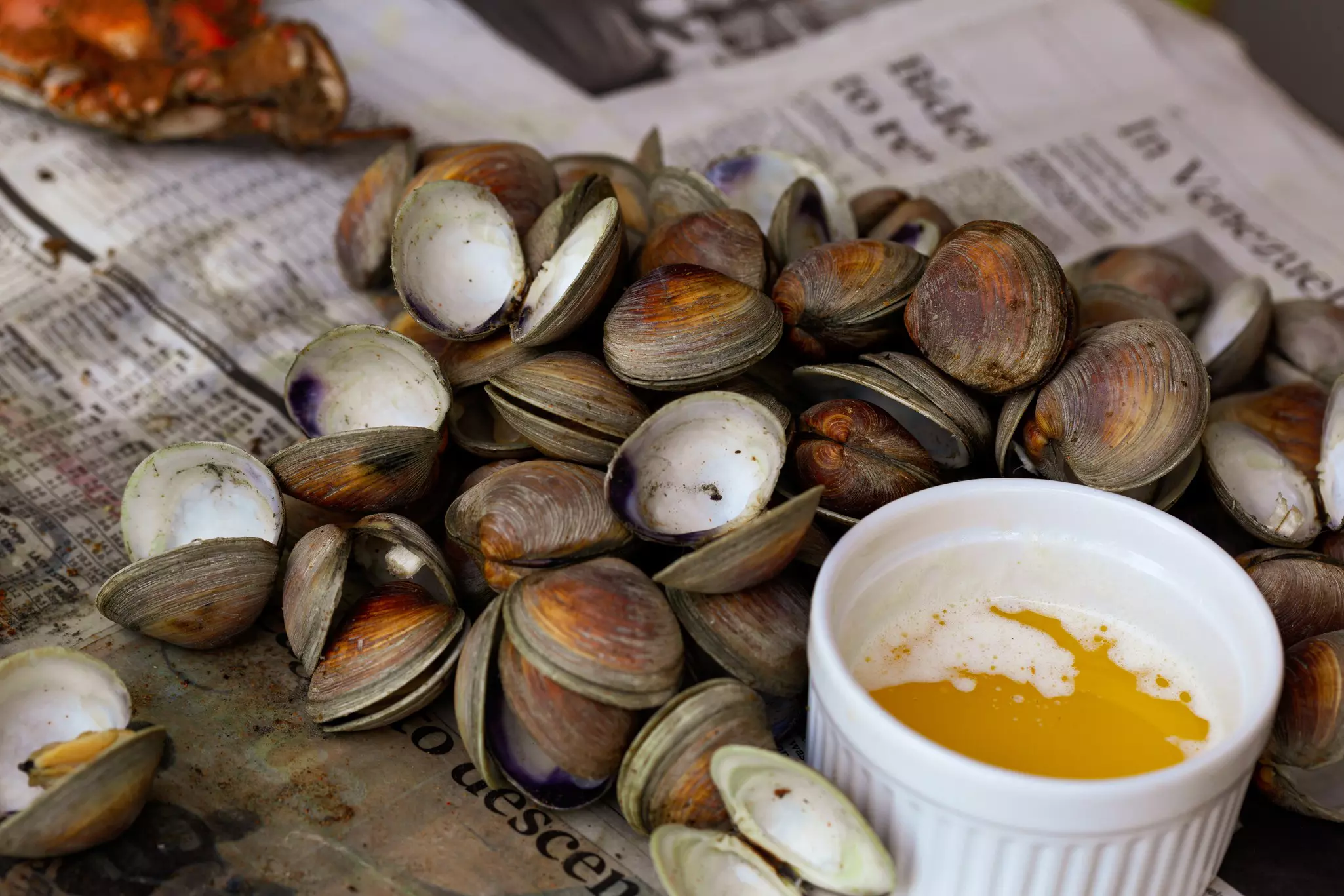 Cooked clams on newspaper, served with butter.