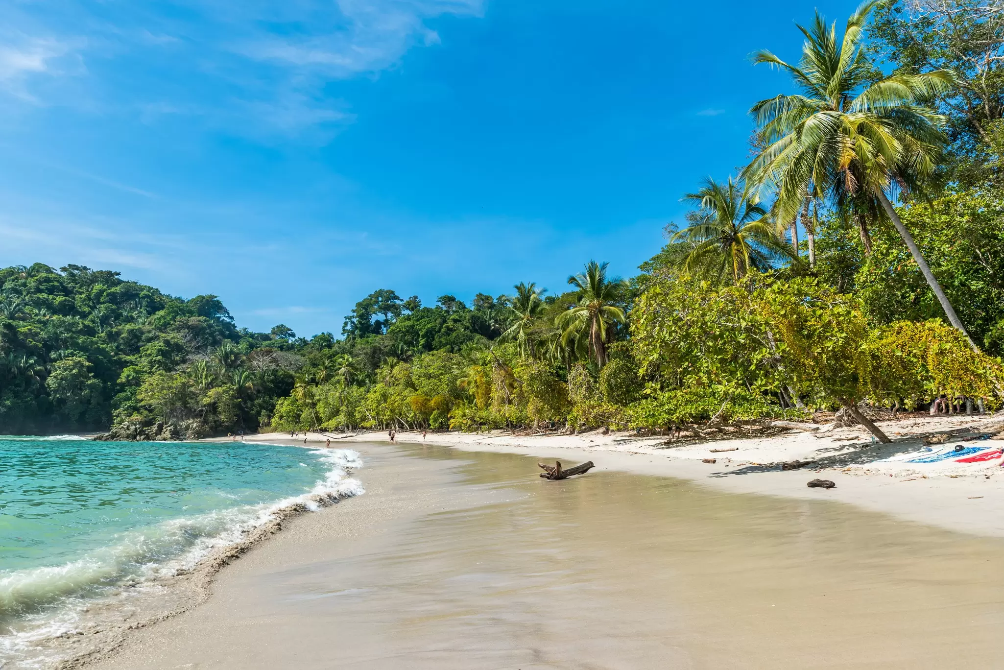 Waves wash onto Manuel Antonio beach on a sunny day in Costa Rica.