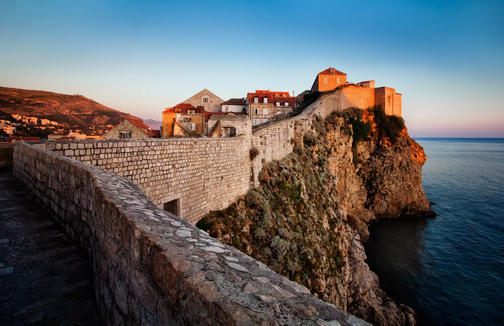 City walls stretch up a slope towards a fortified tower