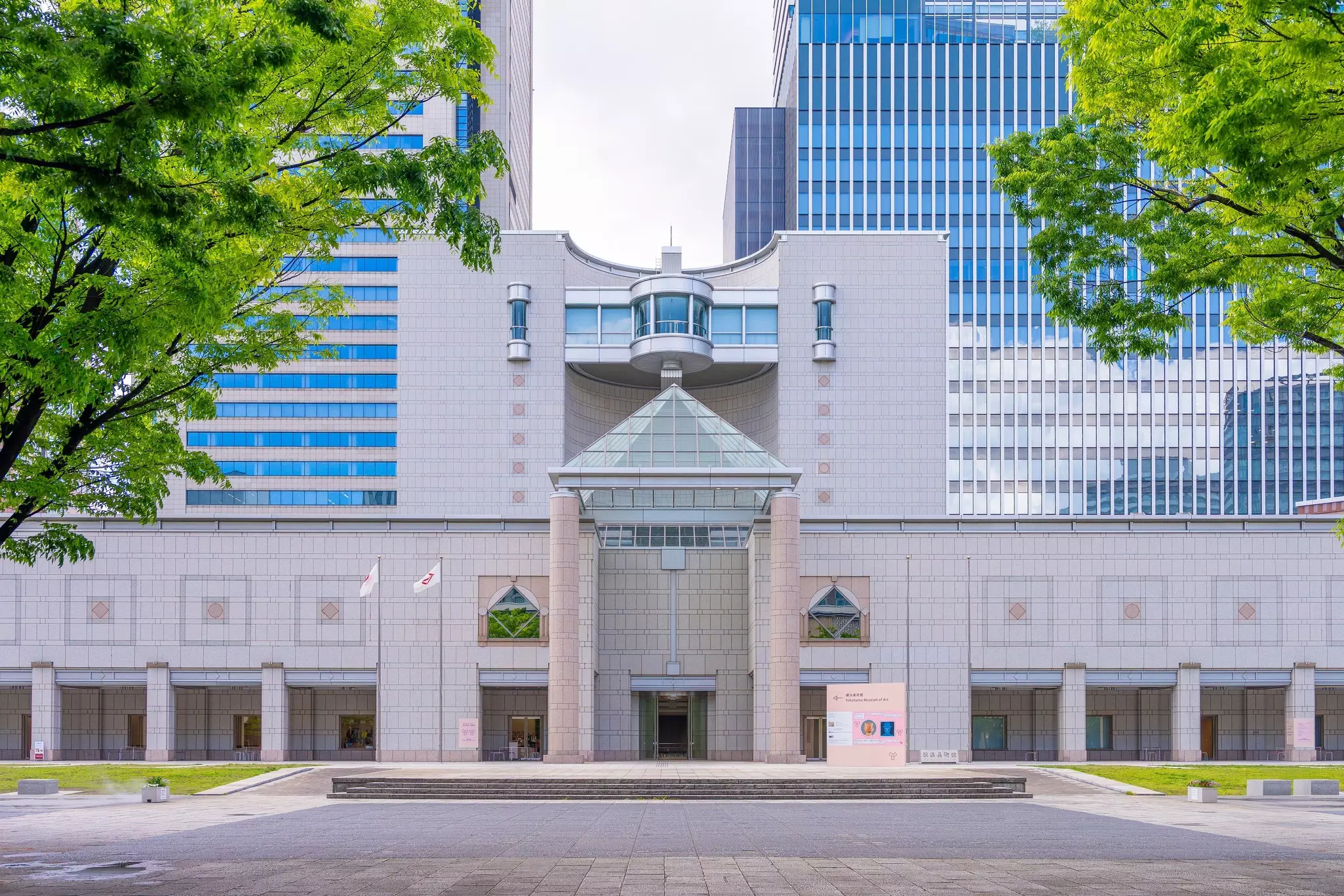 Facade of large white building with concrete courtyard on a sunny day.