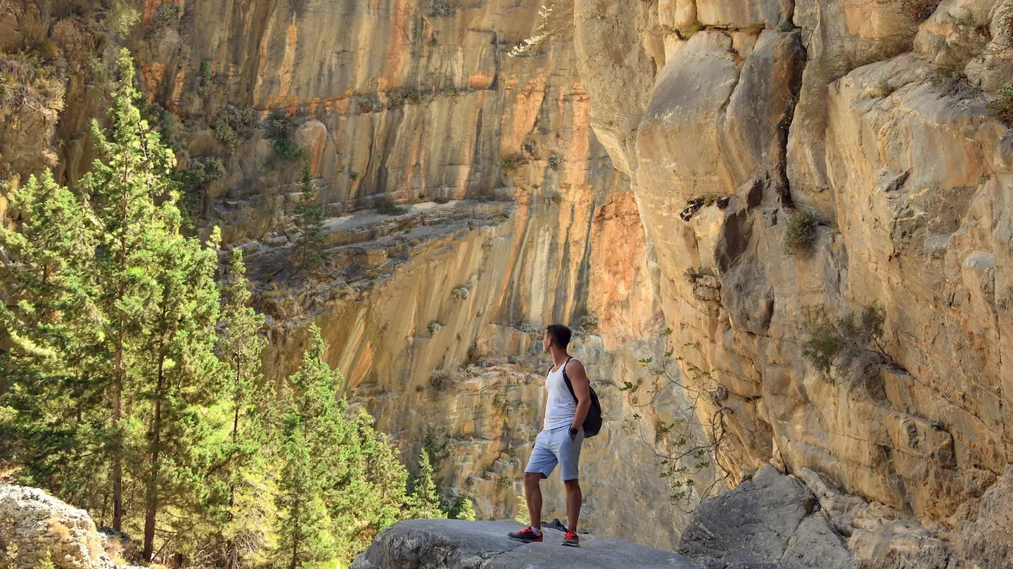 Young male hiker stands on a rock, Samaria Gorge, Crete, Greece