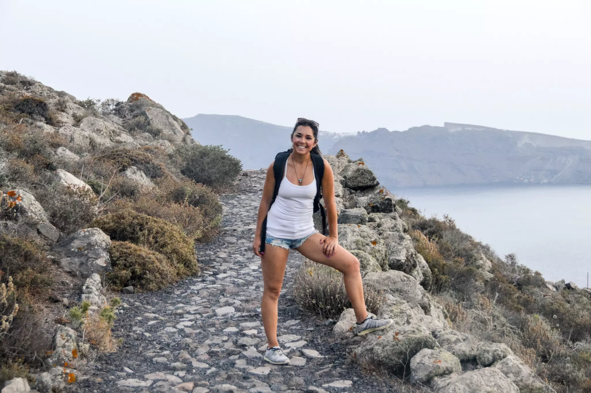 Young woman hiking with panoramic view of Santorini, Greece