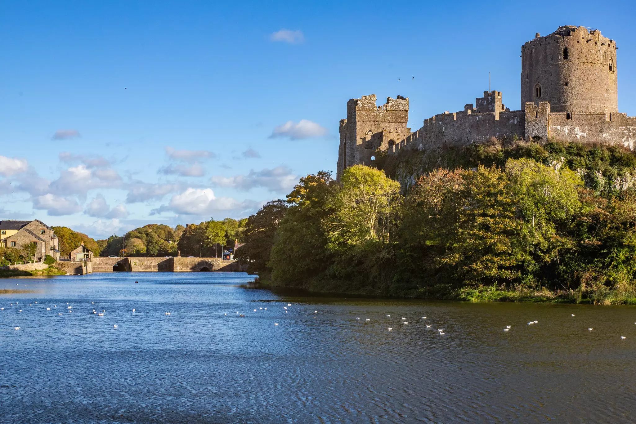 A sunny autumn day showing Pembroke Castle on the Pembroke River, Pembrokeshire, Wales.