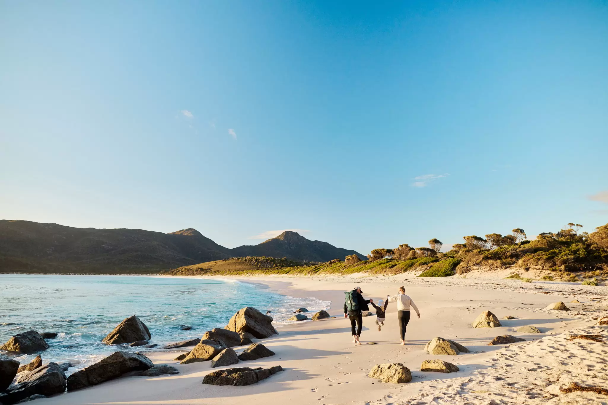 A family walking along the beach at Wineglass Bay in Tasmania, Australia.