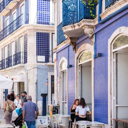 Female diners sit at a table outside a purple-tiled cafe.