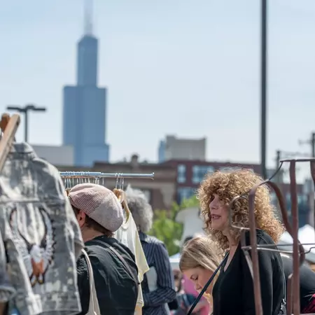 Customers looking at clothing racks at an outdoor vintage market.