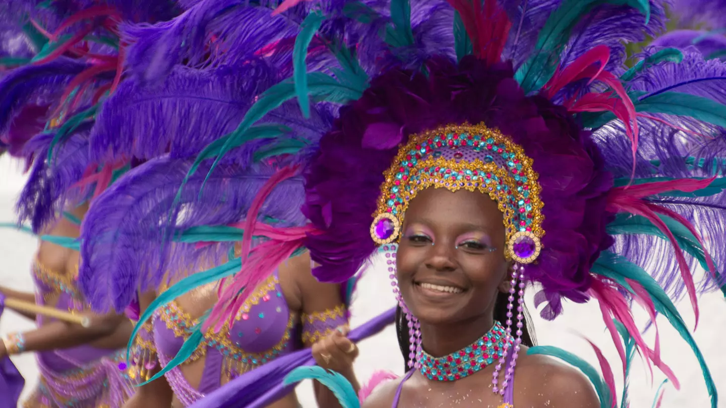 A smiling woman in a purple feathered headdress during Carnival in St Thomas, US Virgin Islands, USA
