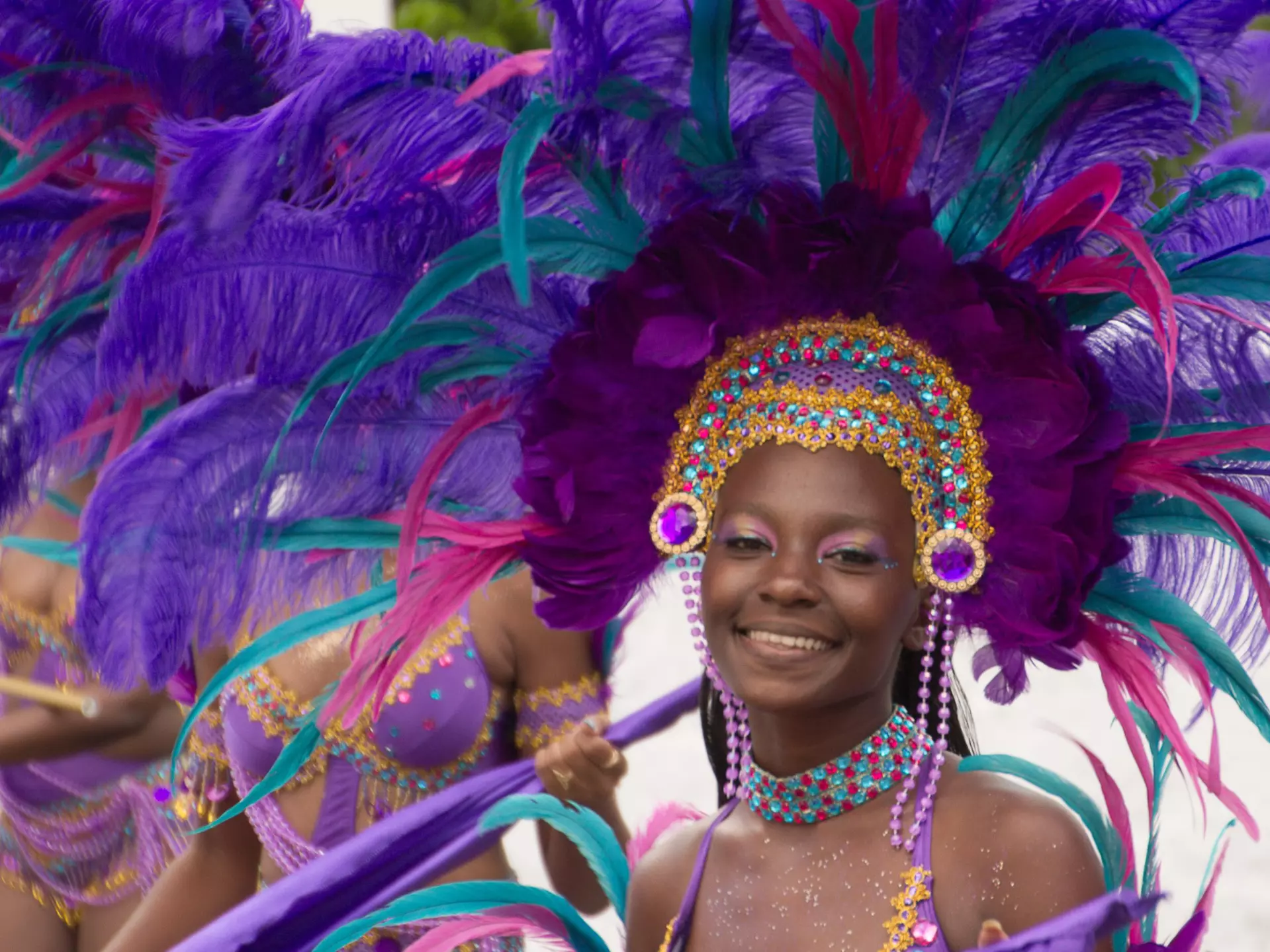 A smiling woman in a purple feathered headdress during Carnival in St Thomas, US Virgin Islands, USA