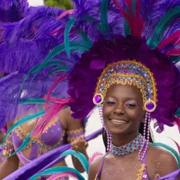 A smiling woman in a purple feathered headdress during Carnival in St Thomas, US Virgin Islands, USA