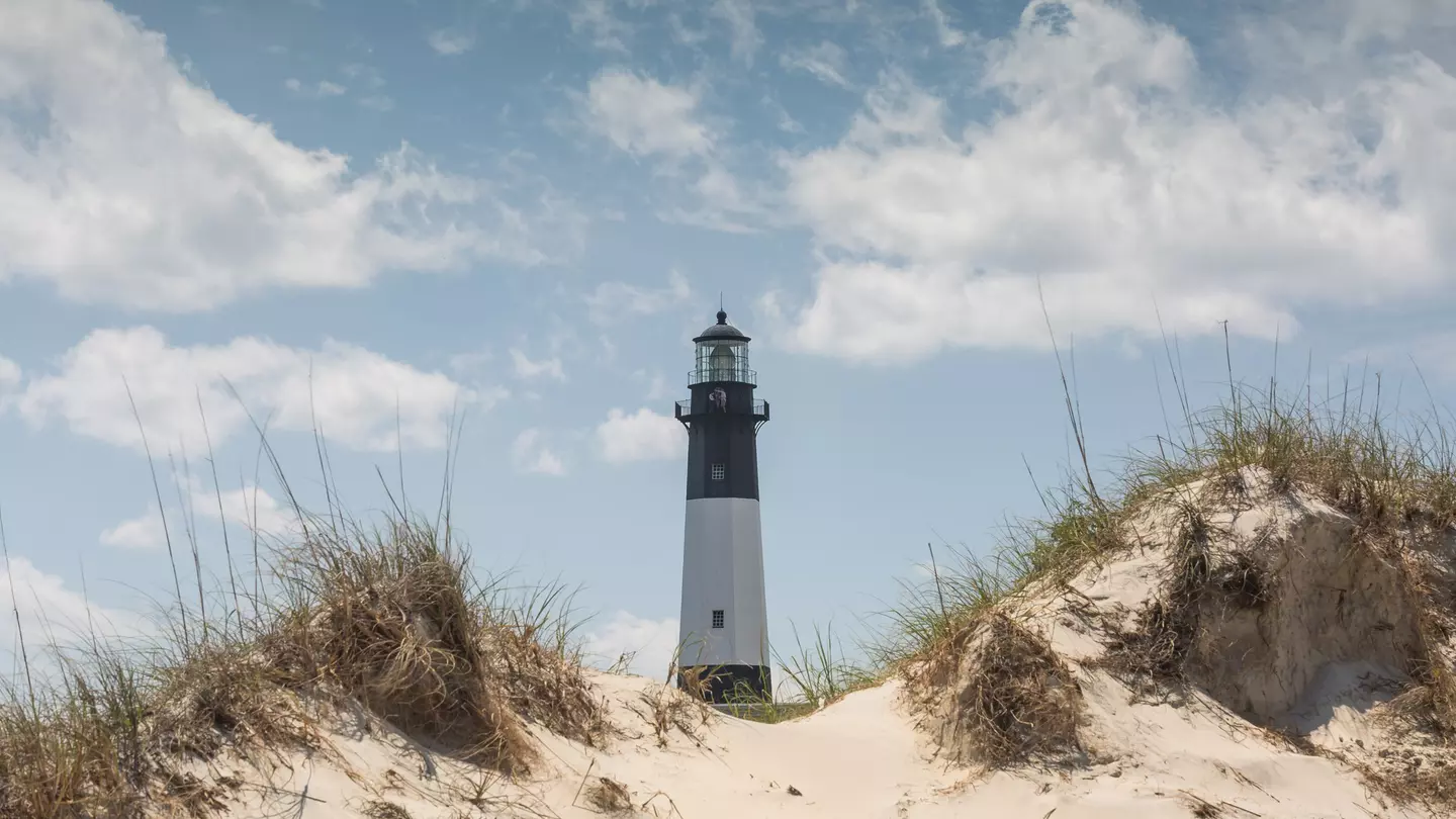 The Tybee Island lighthouse in Georgia emerges from behind sand dunes.