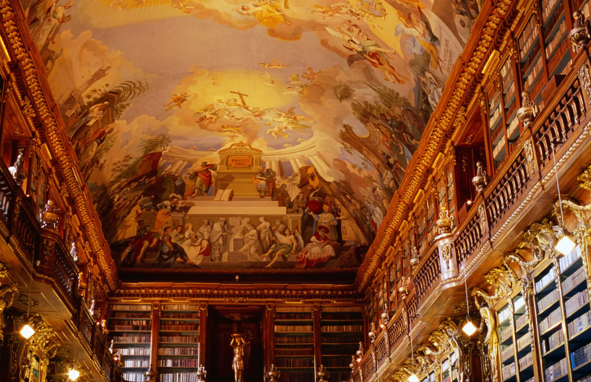 Elaborate ceiling frescoes are seen in the reading room of a historic library, Prague