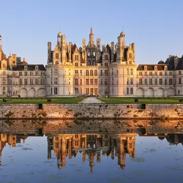 The ornate exterior of the Château de Chambord with its reflection in the lake at the front of the building