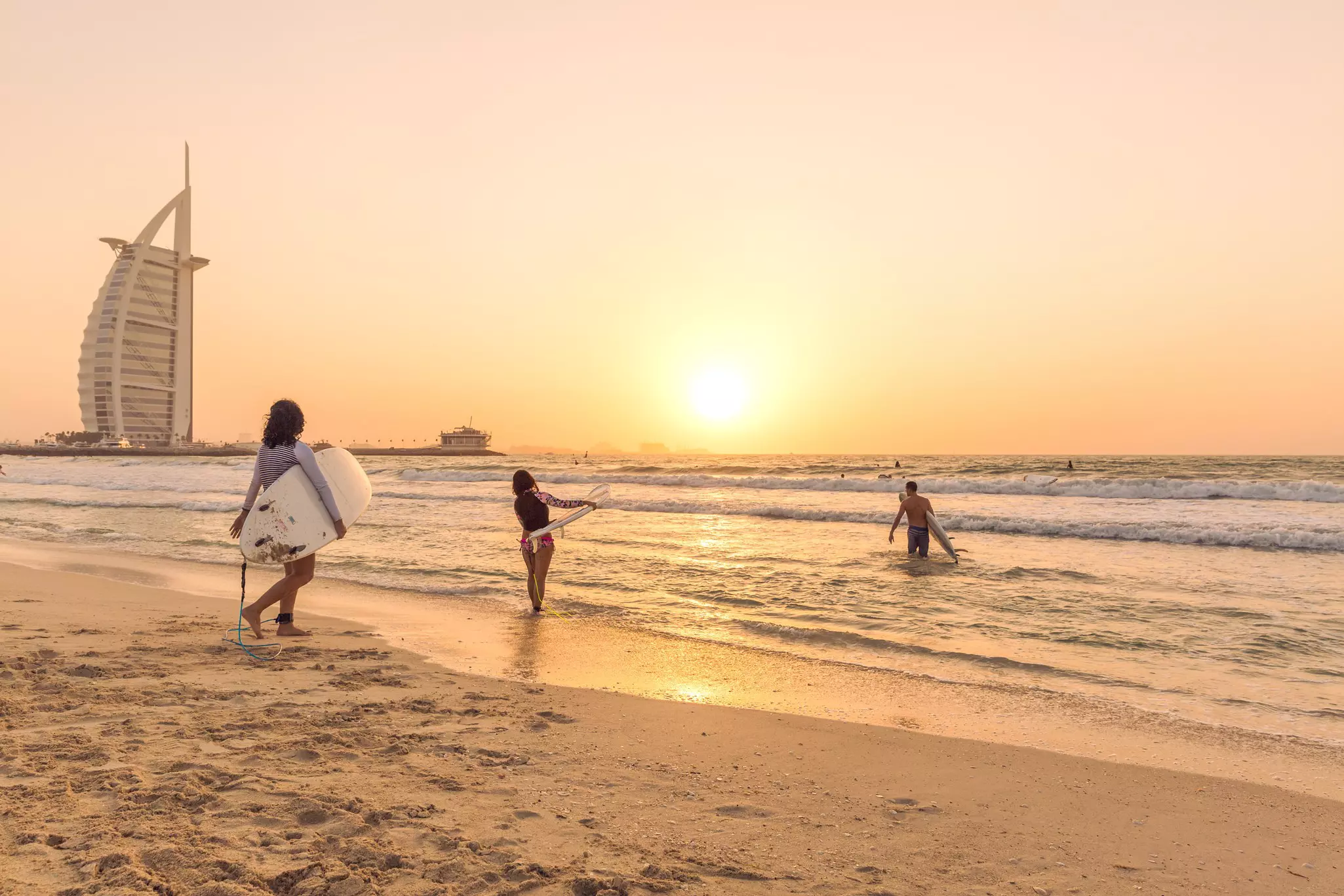 Surfers on the beach near Burj Al Arab, Dubai, United Arab Emirates