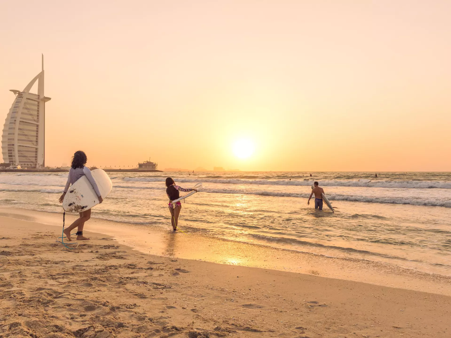 Surfers on the beach near Burj Al Arab, Dubai, United Arab Emirates