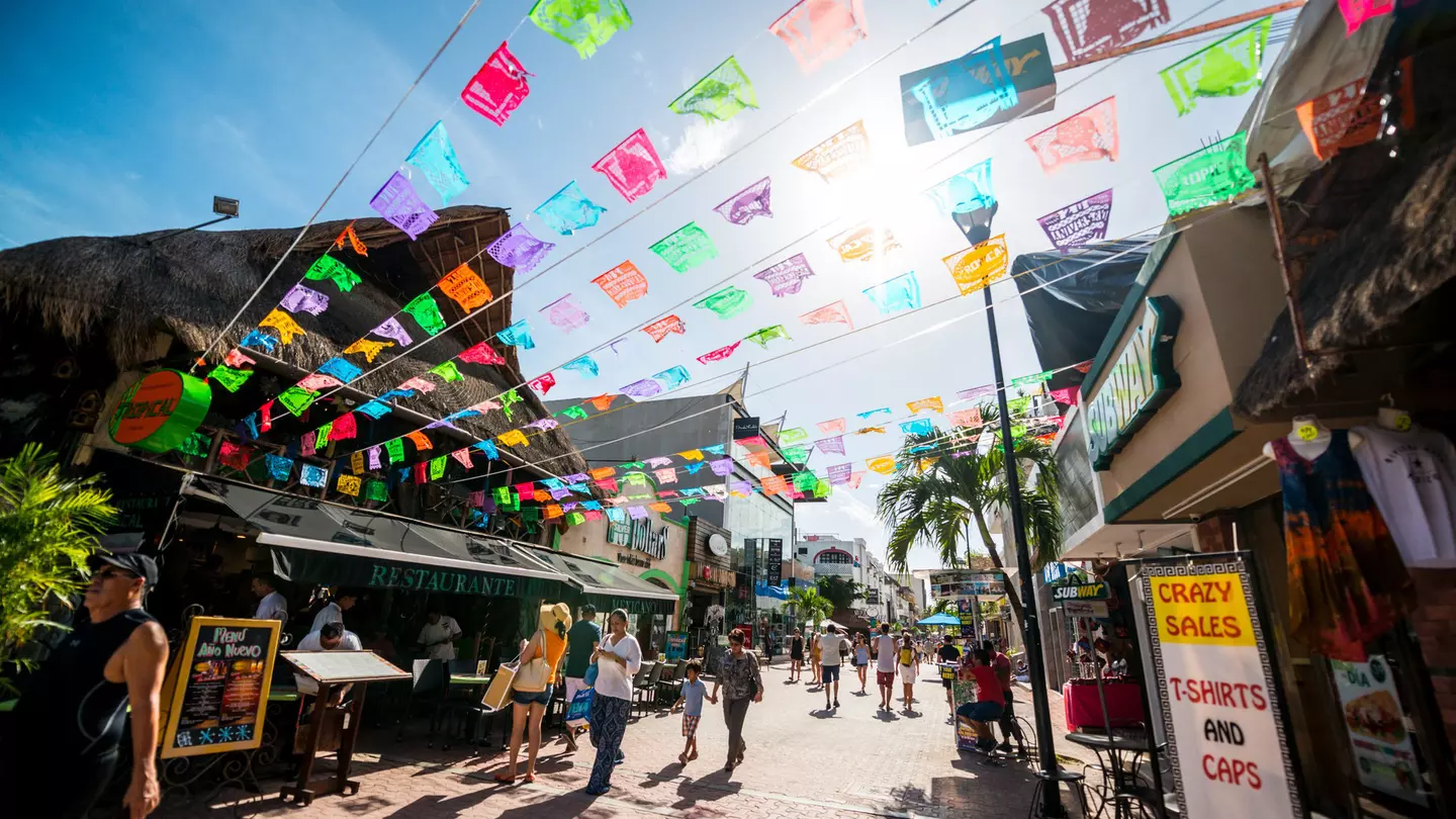 Tourists exploring a predestrianized shopping street with colorful bunting fluttering in the breeze