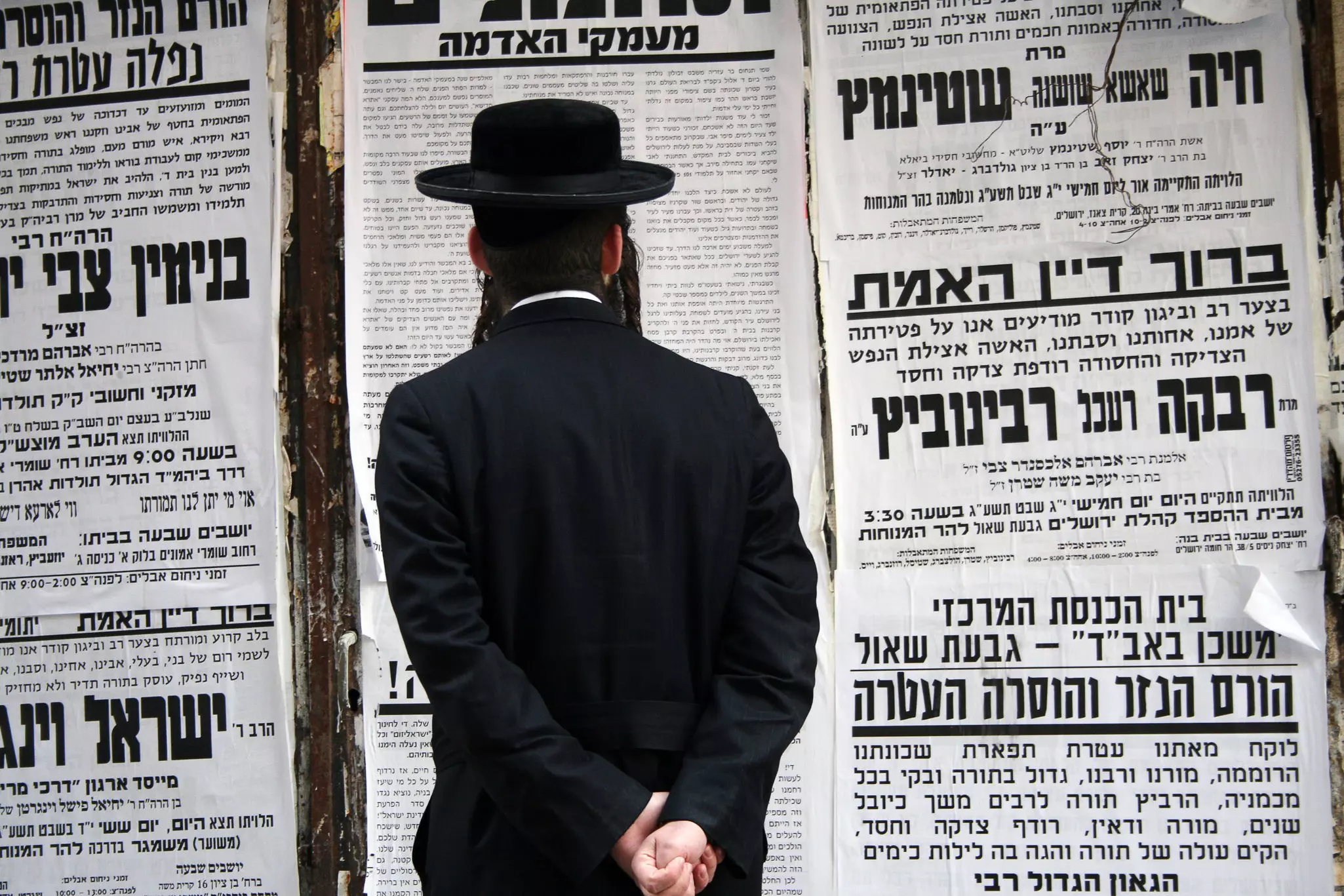Man dressed in traditional clothing stands reading on the street in the ultra-orthodox area of Jerusalem, Mea Shearim