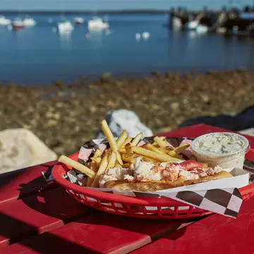 Lobster roll and french fries on a waterfront harbor in Maine. jenlo8/Shutterstock