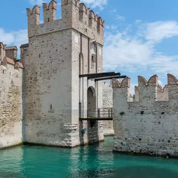 The Castello Scaligero di Sirmione emerges from the crystal clear water in the harbor.