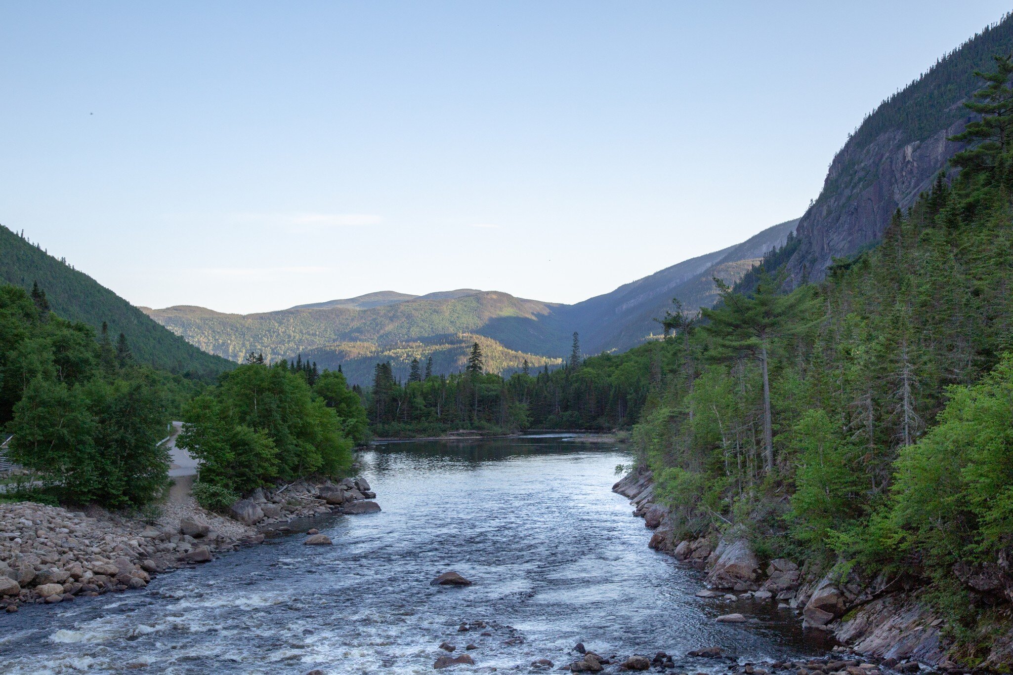 View of a river in Parc National des Hautes Gorges de la Rivière Malbaie, Canada, with mountains in the background.