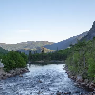 View of a river in Parc National des Hautes Gorges de la Rivière Malbaie, Canada, with mountains in the background.