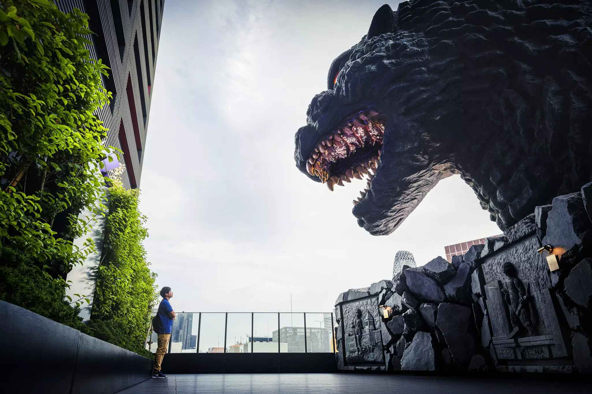 A person facing a statue of Godzilla.
