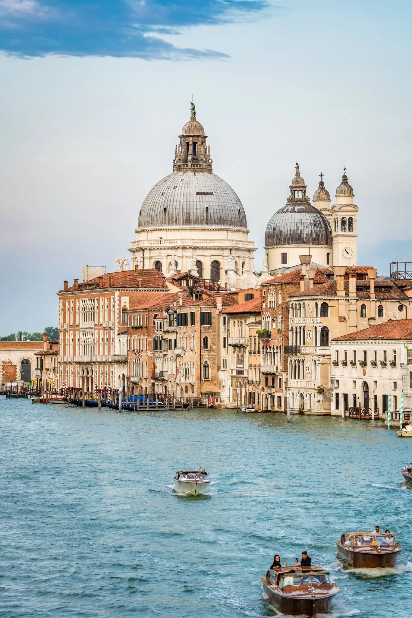 Pastel-colored buildings line a canal; an imposing church rises above the skyline.