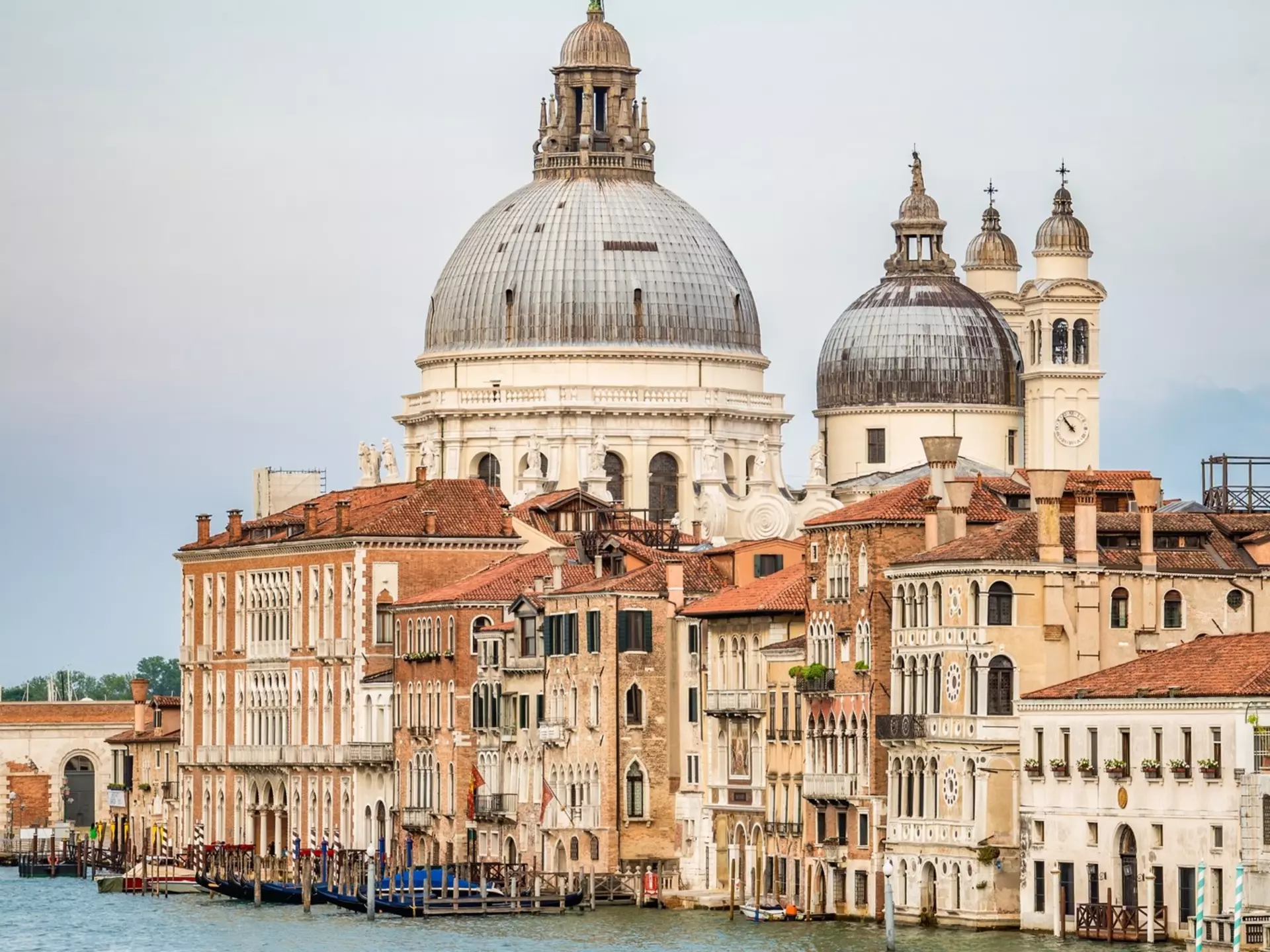Pastel-colored buildings line a canal; an imposing church rises above the skyline.