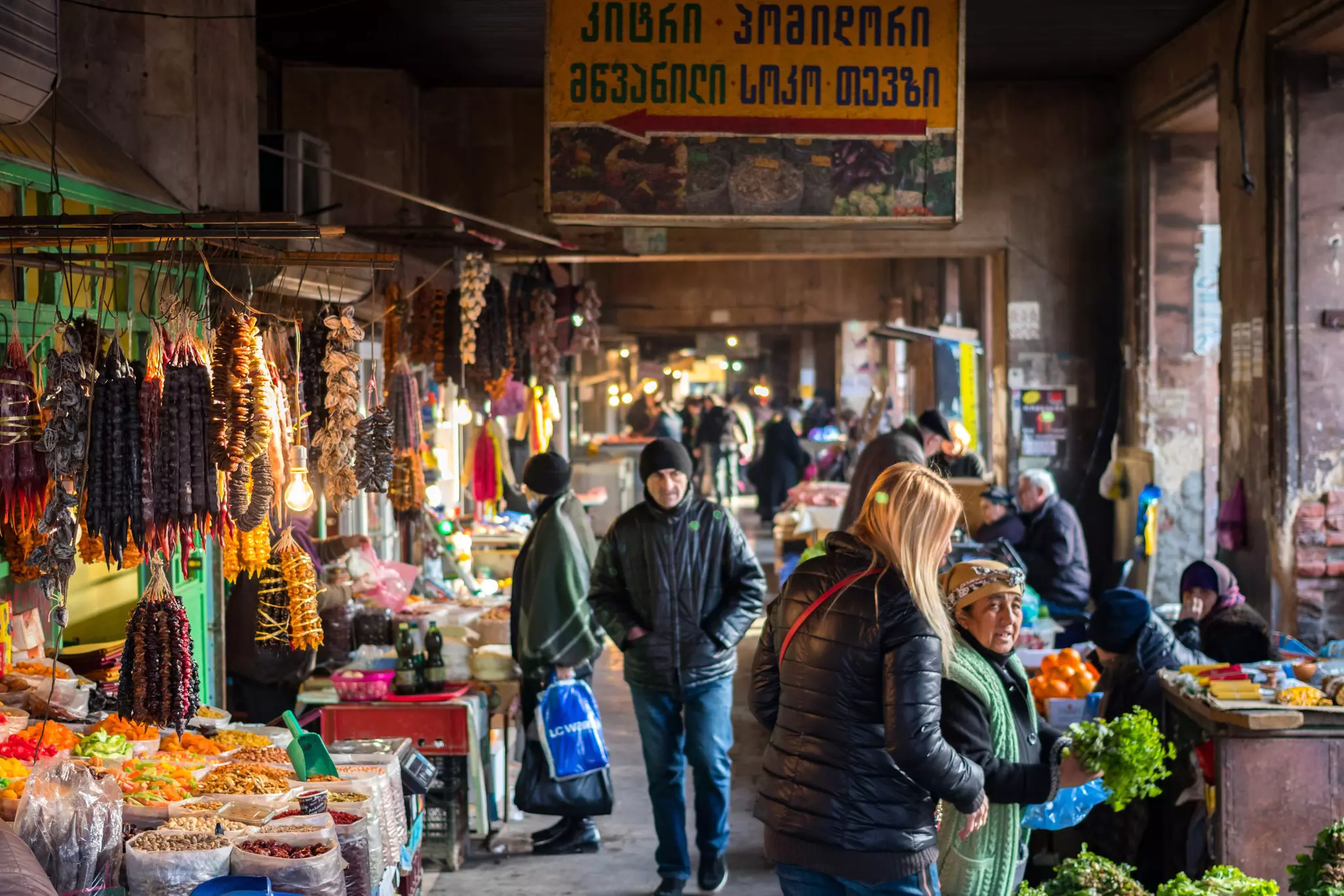 Shoppers in a market with stalls selling produce and food items.