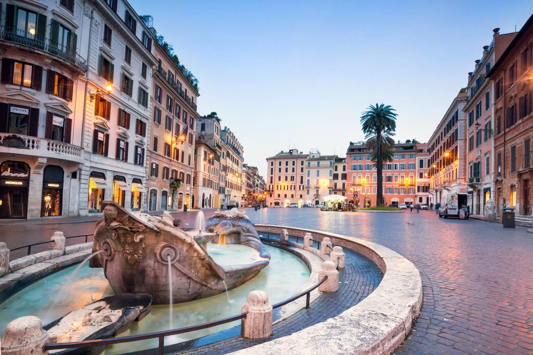 A low-level sculpture shows a boat sinking in a fountain in a city square