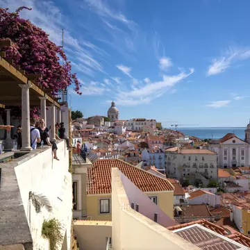 People at a viewpoint over red roofs of a hilly city