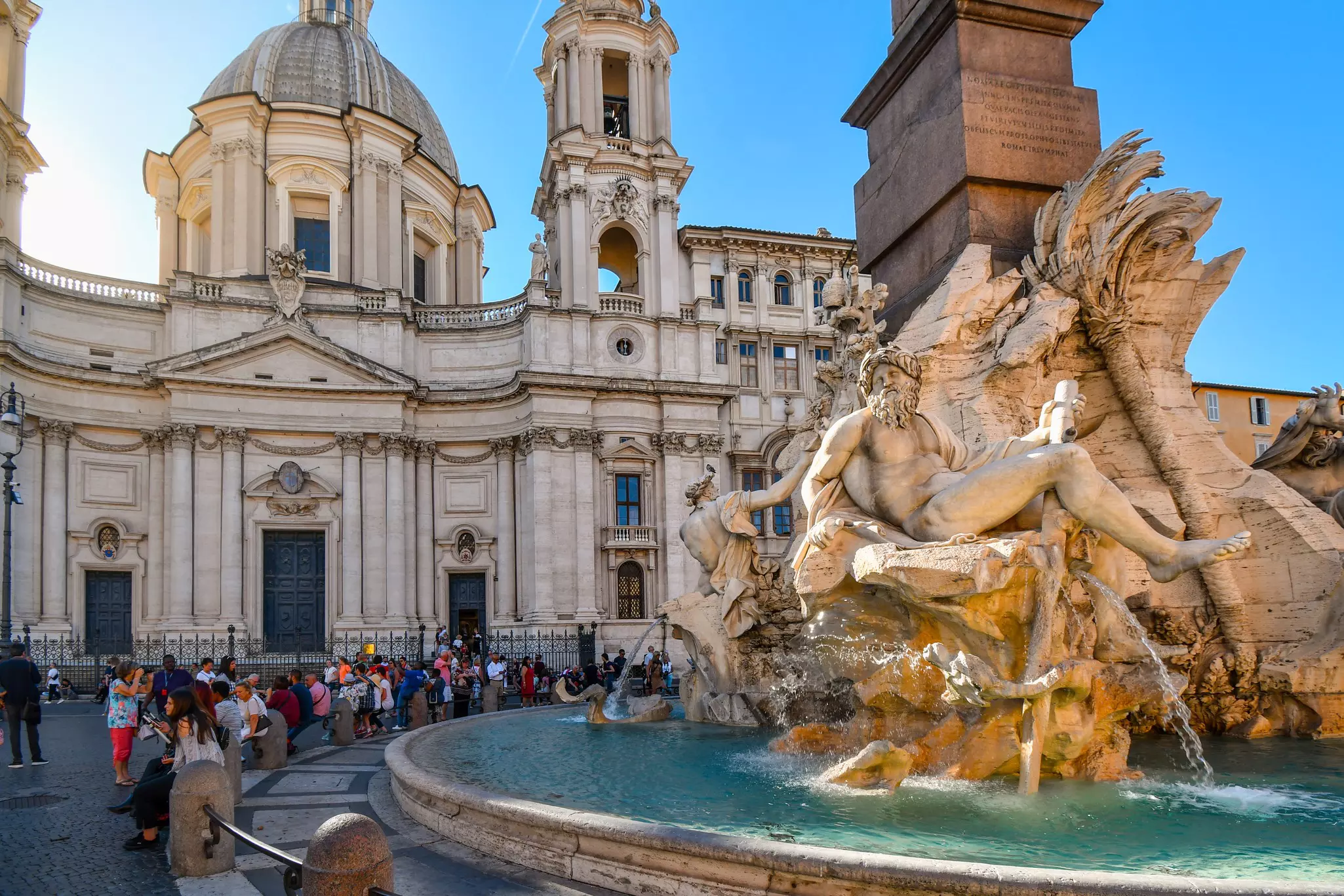 Rome, Italy - September 29 2018: Tourists relax in the shade of the Sant'Agnese in Agone church as the sunlight hits the Bernini designed Fountain of the Four Rivers in Piazza Navona., License Type: media, Download Time: 2025-03-13T13:34:17.000Z, User: katelyn.perry_lonelyplanet, Editorial: true, purchase_order: 65050 - Digital Destinations and Articles, job: wip, client: wip, other: Katelyn Perry
