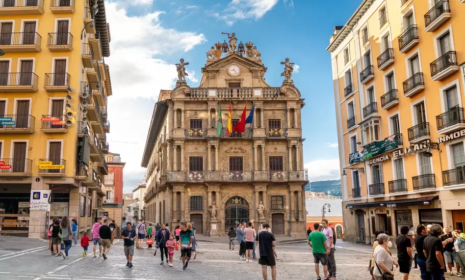 People wander through a city square lined with buildings.