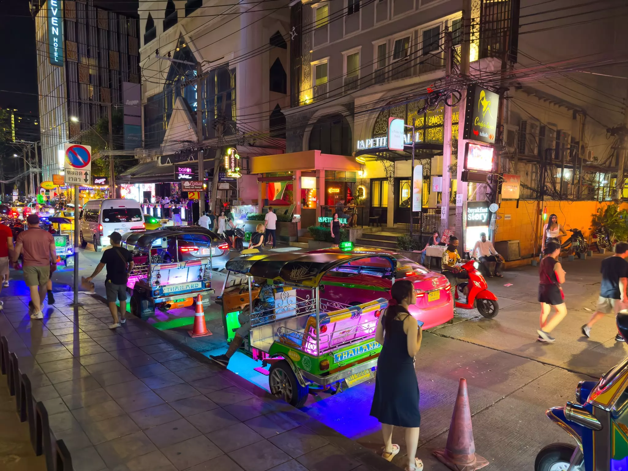 A busy street at night with colorful small vehicles
