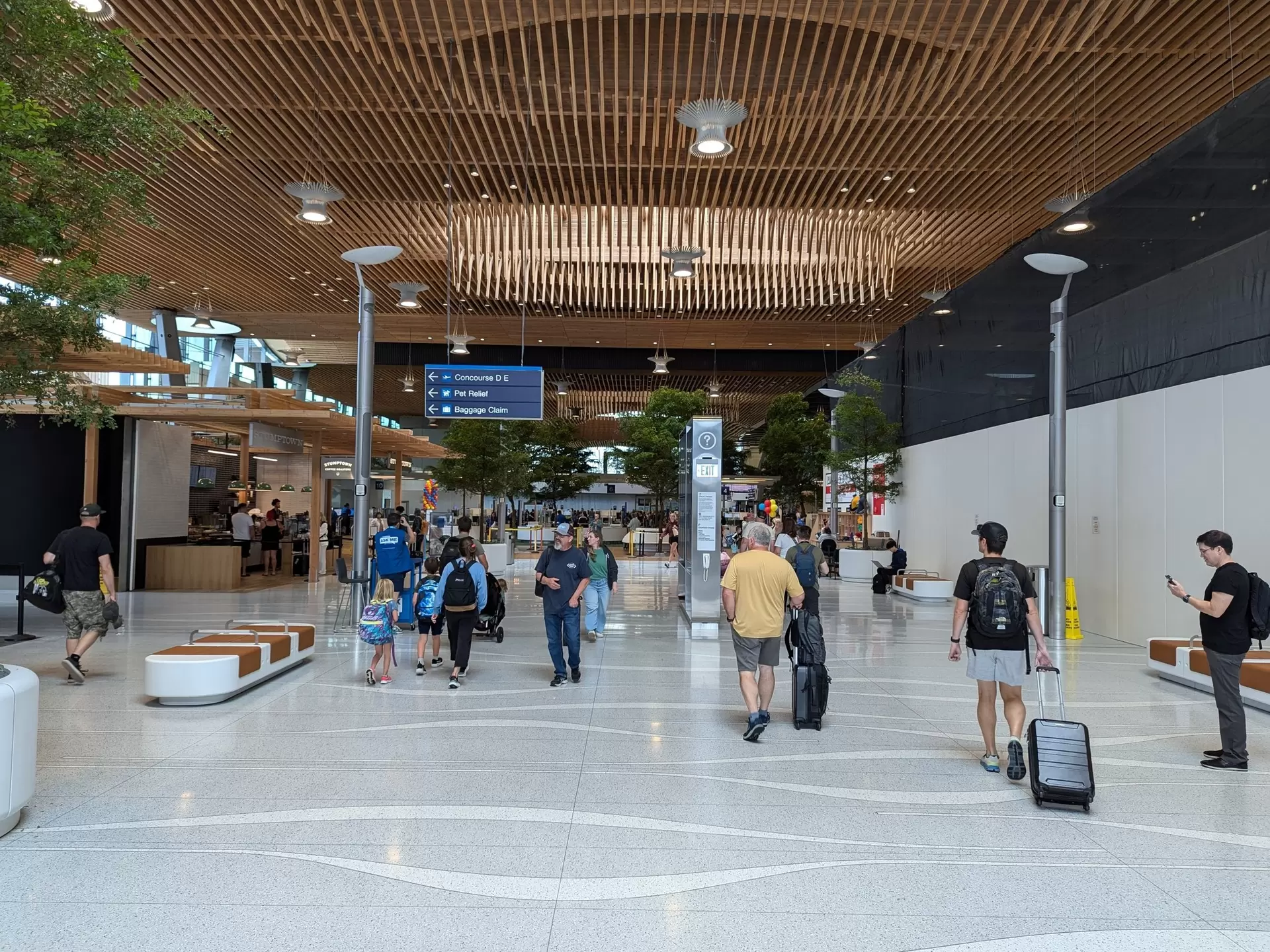 Passengers walk through an airport concourse with their luggage in Portland, Oregon, USA.