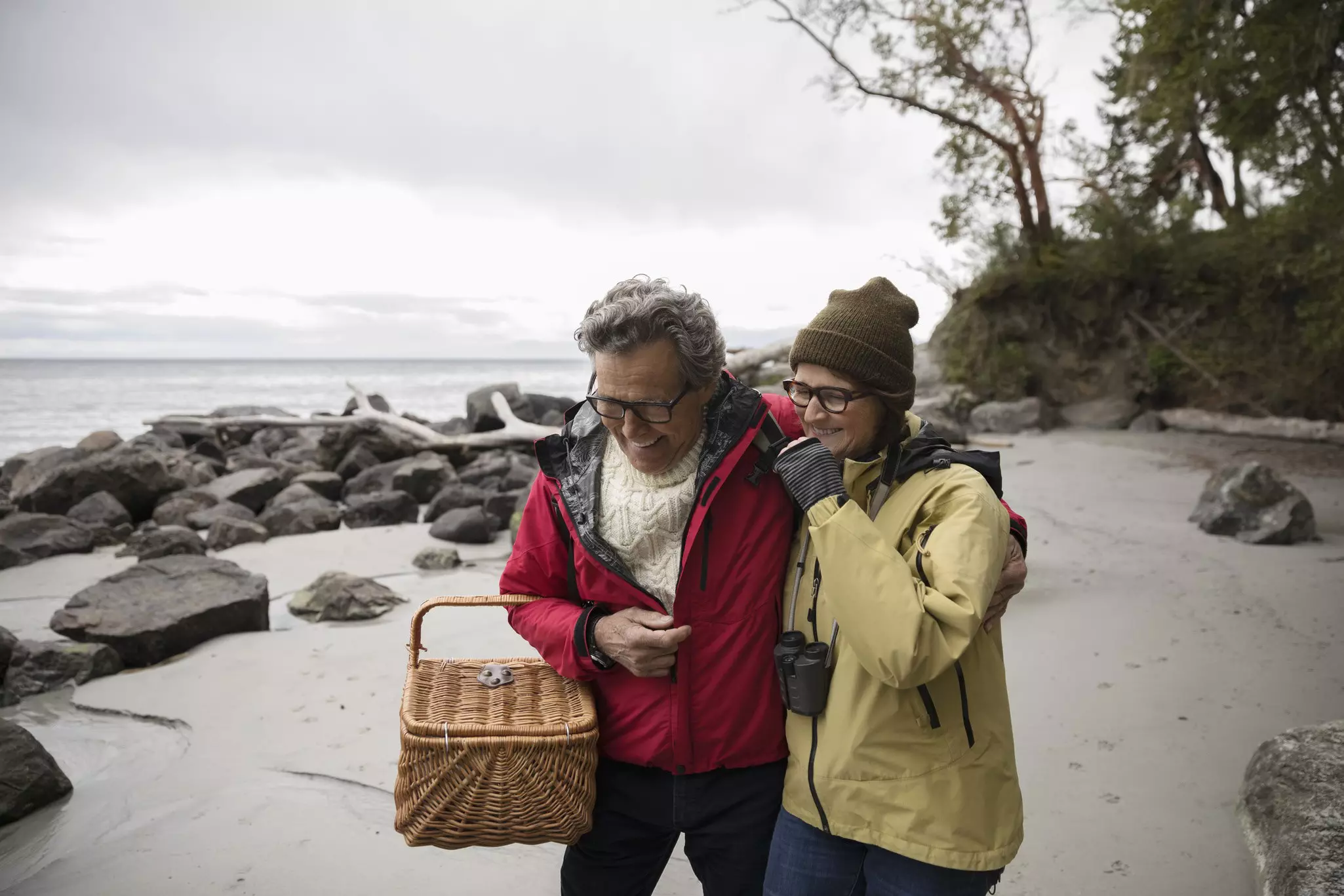 Affectionate senior couple with a picnic basket on a rugged beach.