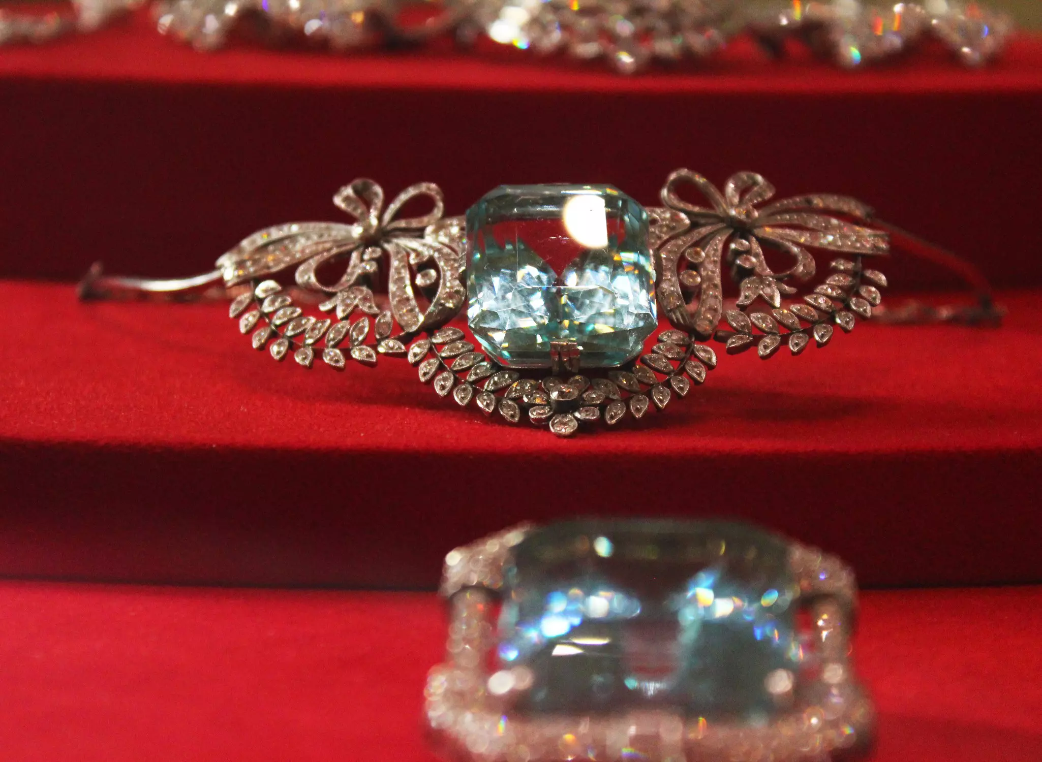A piece of jewelry with clear and light blue stones sits on a red display at a museum in Egypt.