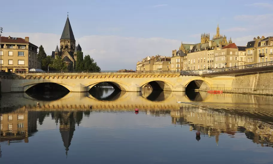 Metz, France: arched Moyen bridge over the Moselle, the Temple Neuf spire at left and the cathedral above houses at right