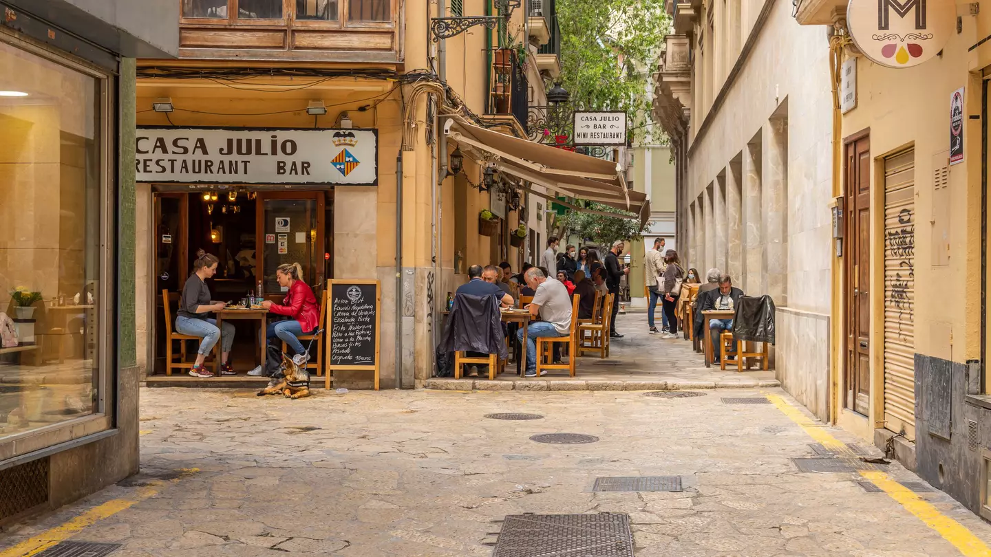 A waitress with a face mask and disposable gloves takes an order in a cafe