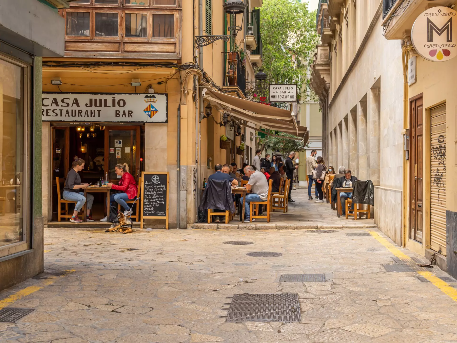 A waitress with a face mask and disposable gloves takes an order in a cafe