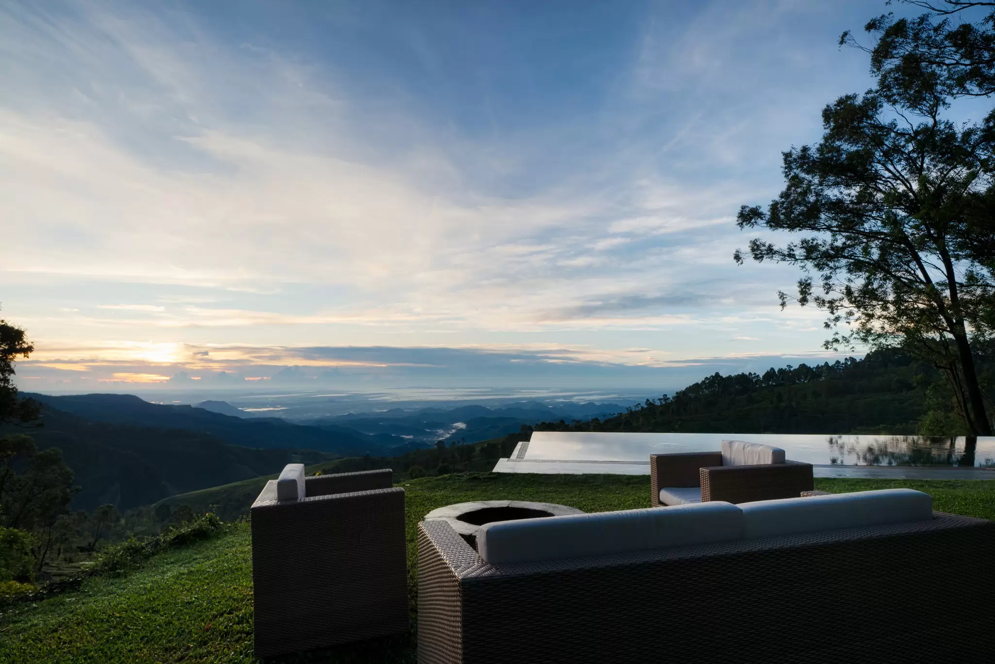 A hilltop terrace with a seating area, infinity pool and views of the surrounding countryside.