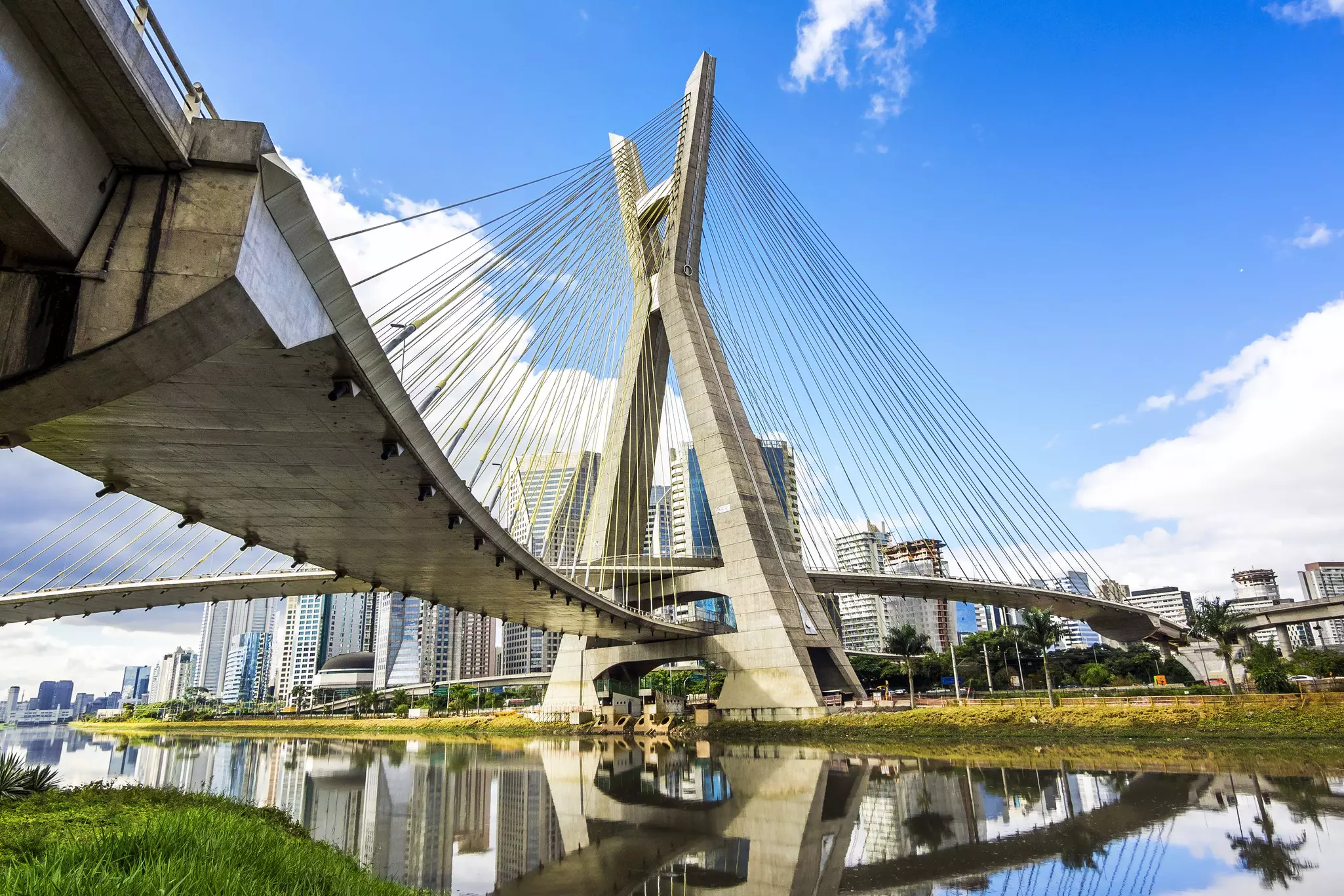 A suspension bridge over a river in a high-rise city