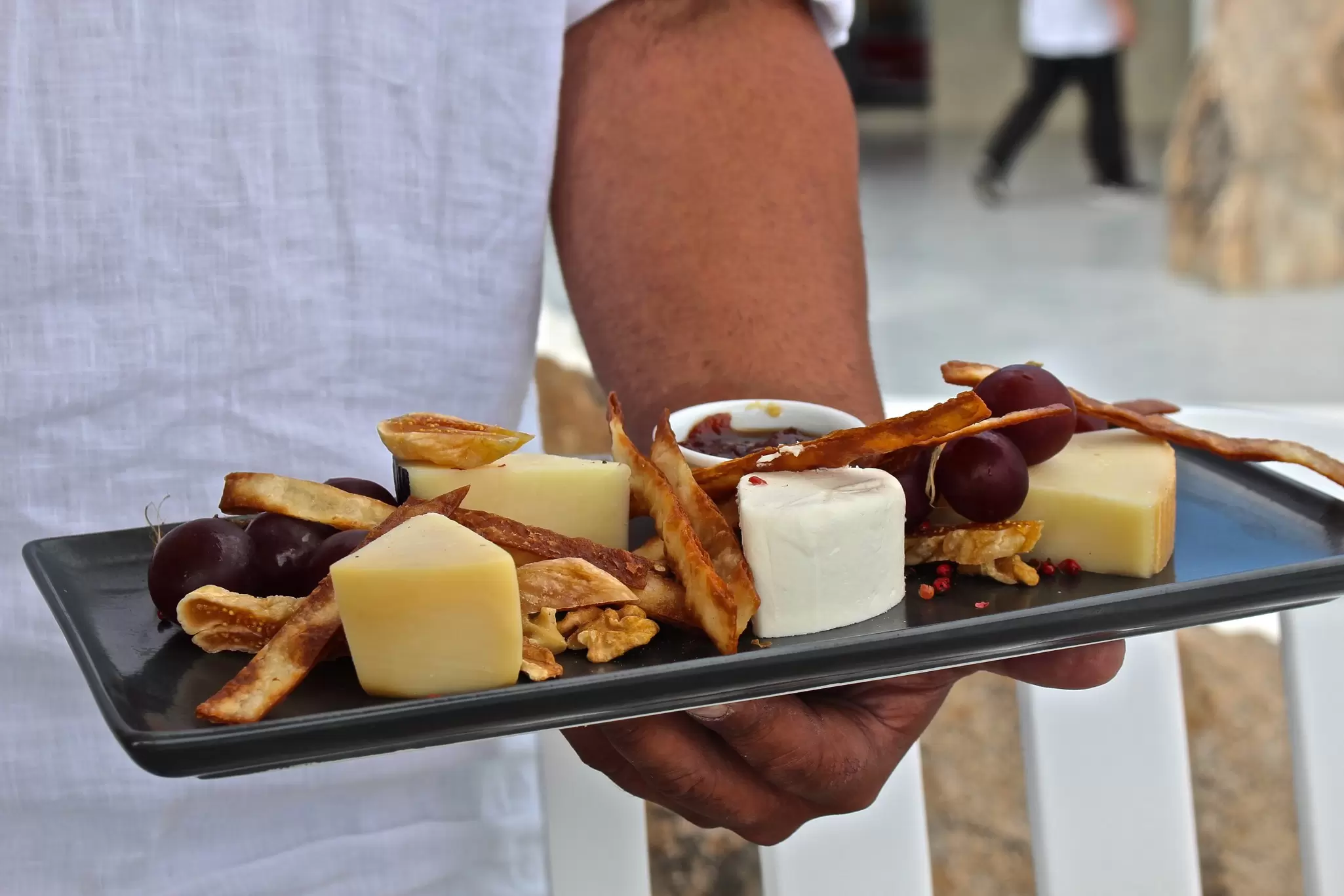 A waiter holding a plate of local cheeses at a restaurant in Mykonos, Greece. 