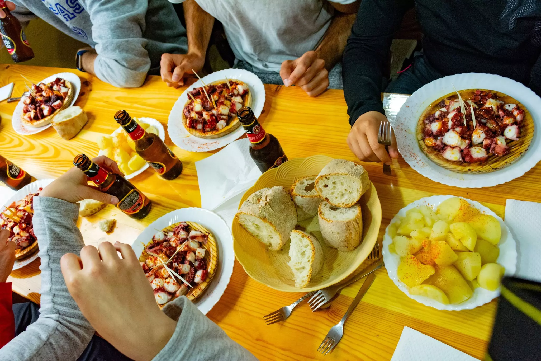 A table with Galician-style octopus, potatoes, beer and people gathered on the Camino de Santiago, Spain