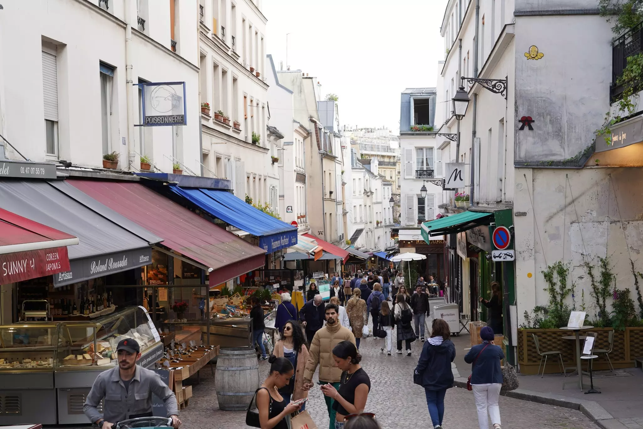 People walking in Rue Mouffetard, a famous pedestrian street in the Latin Quarter.
