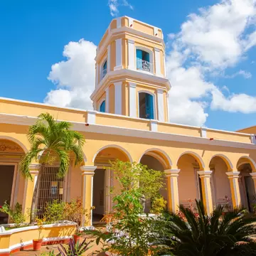 Palacio Cantero, Trinidad, Cuba: yellow and white arcaded courtyard with palms and potted plants below a tiered lookout tower