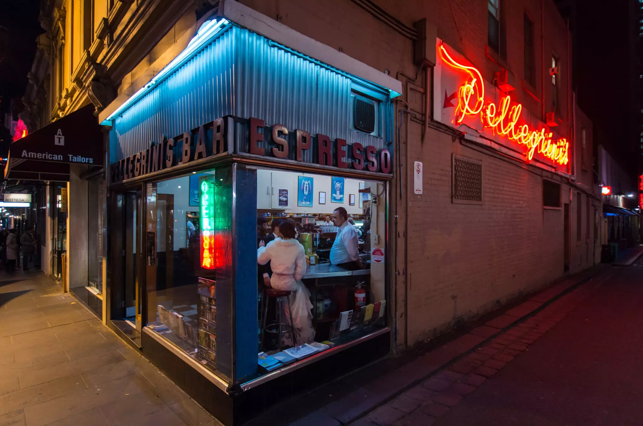 Exterior of Pellegrini's Espresso Bar in Melbourne at night with illuminated neon signs