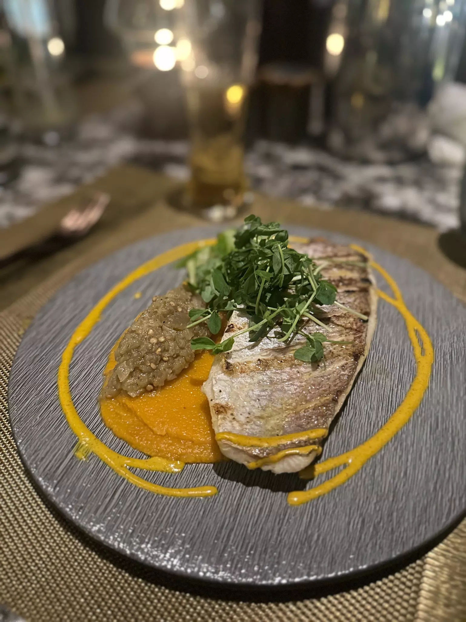 A piece of fish served with a puree on a gray plate.