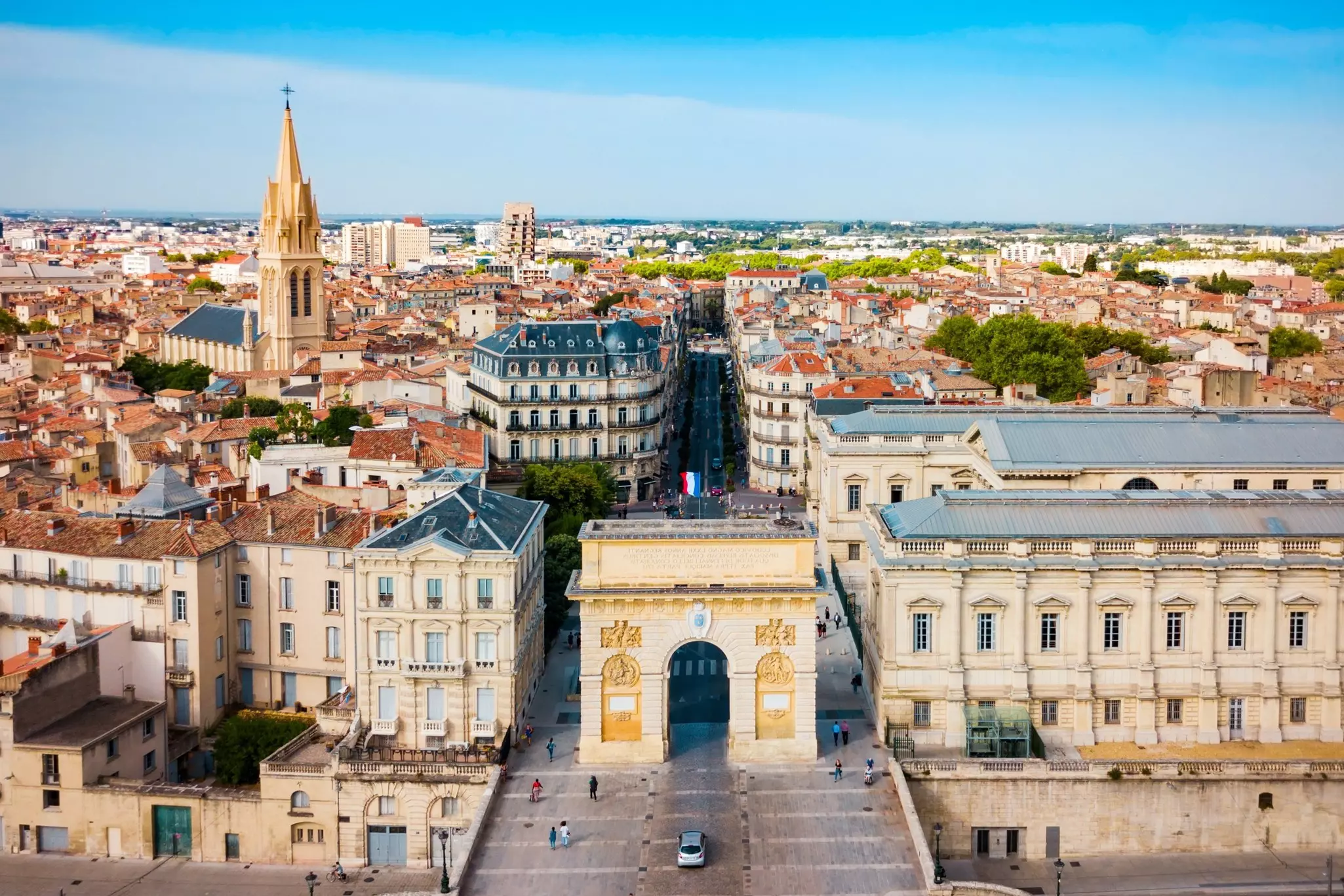 An aerial view of a large arch in a city square surrounded by elegant buildings.