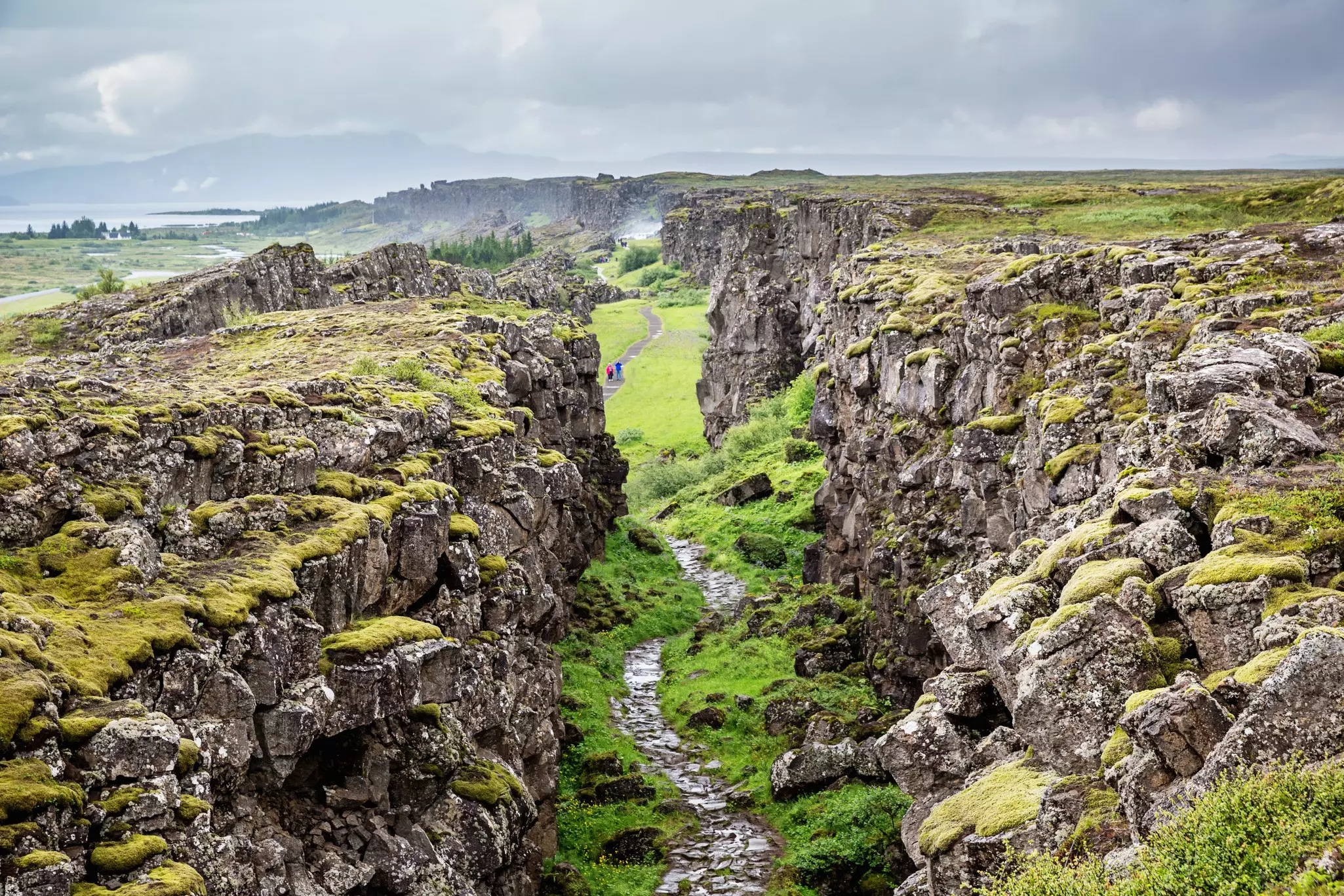 People follow a pathway through a narrow rocky passage.